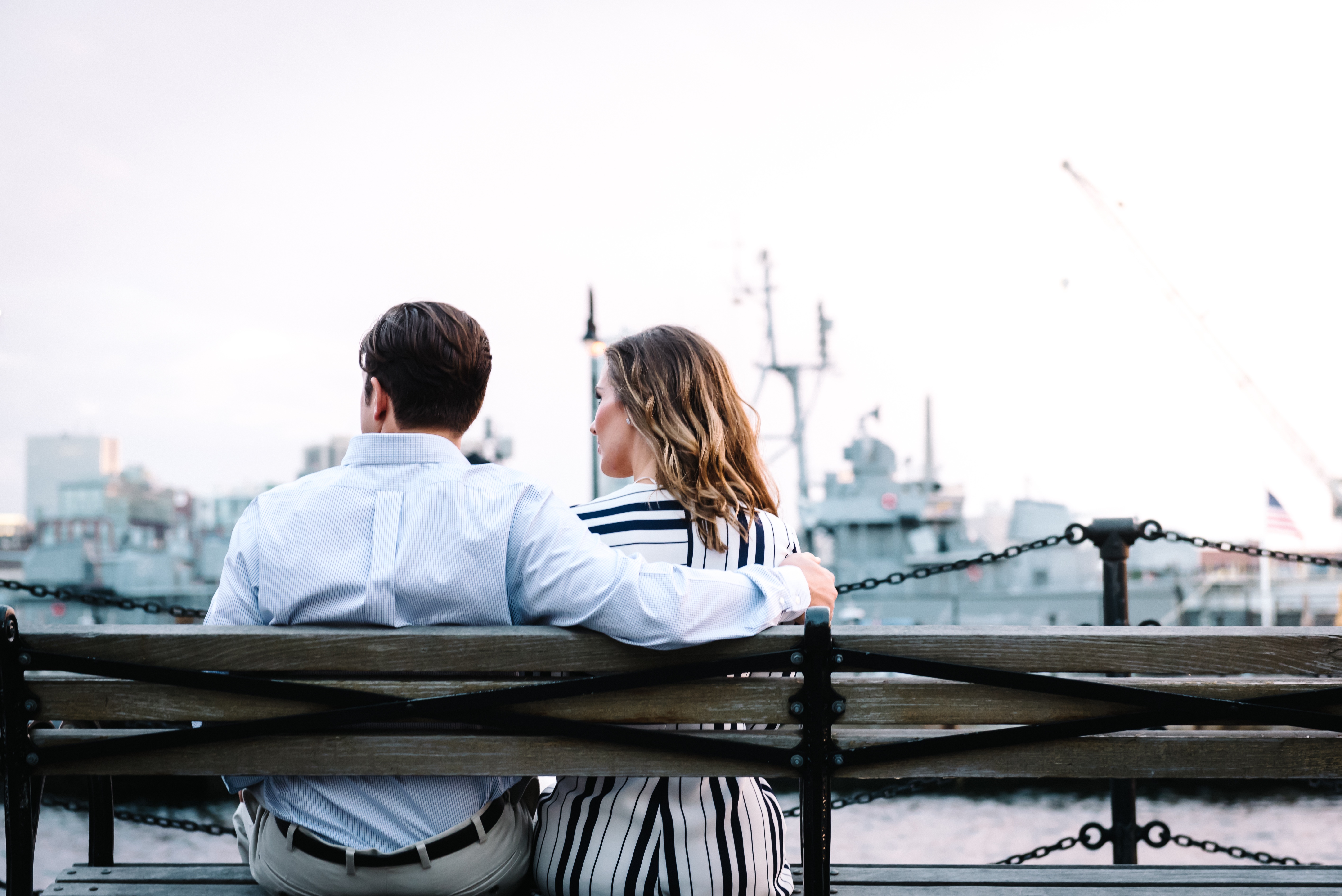 Couple sitting on a bench looking out over a harbour